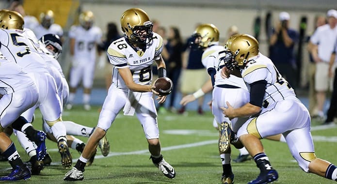 St. Pius X quarterback Reed Egan (#18) hands off to fullback Dalton Wilson (#42). His rushing yards during a final offensive drive were crucial to setting up the game winning field goal by Michael Mathews. Photo By Rob Buechner