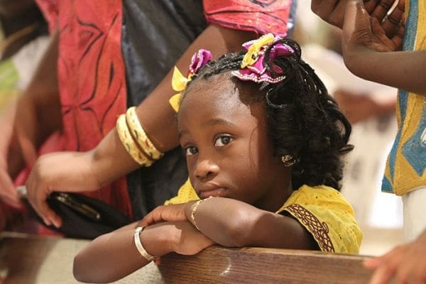Four-year-old Harriet Sarr, a member of St. Theresa of the Child Jesus Church, Douglasville, looks toward her mother, a member of the Gambian Christian Organization of Atlanta choir. Photo By Michael Alexander