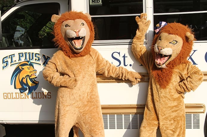 The St. Pius X High School Golden Lion mascots, Rebecca Price, left, and Maddie Marburger, hang out by the school van bearing the Golden Lion logo. Photo By Michael Alexander