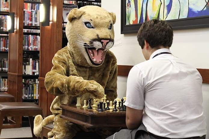 The Holy Spirit Prep School Cougar mascot, Matt Markham, passes the time playing a game of chess with junior Julian Vissenberg. Photo By Michael Alexander