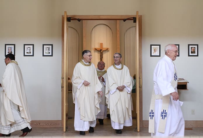 Two of Holy Cross Churchâs former pastors, Msgr. Paul Fogarty, left center, and Father Ed OâConnor, right center, exit the sanctuary following the 50th anniversary Mass honoring its founders and former pastors. Father OâConnor was the homilist for the July 26 liturgy. Photo By Michael Alexander
