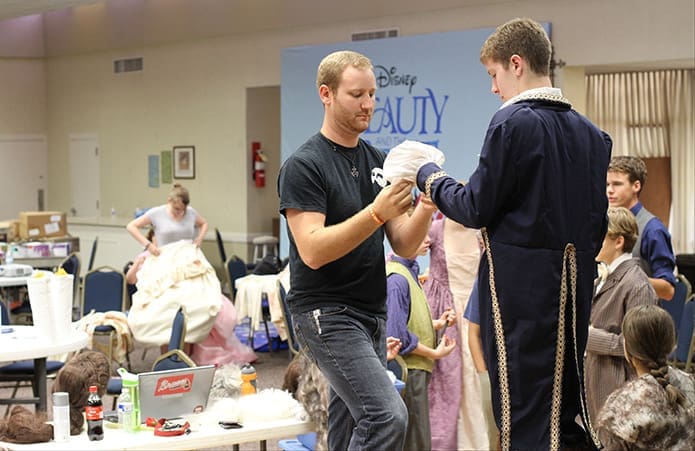 Matthew Thornton, left, director and choreographer for the production of Disneyâs Beauty and the Beast Jr., makes some costume adjustments for Spencer Lail, who is cast as the Beast and Prince. The proceeds from the three productions, the weekend of July 18-20, benefited the parishâs St. Martin de Porres food pantry. Photo By Michael Alexander