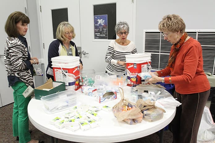 (L-r) Lou Hightower, Jane Miller, Barbara Kerner and Patricia Krull walk around a table gathering bags of personal hygiene items for soldiers. Photo By Michael Alexander