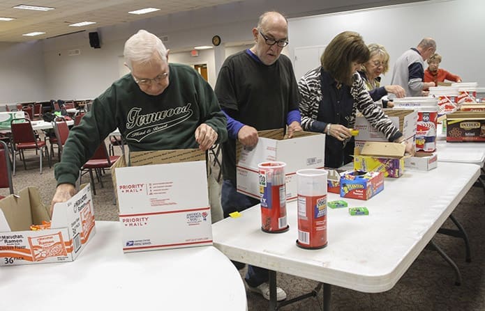 (L-r) Holy Cross Church parishioners Jim Towhey, Denis Clos, Lou Hightower, Jane Miller, Bob DeSantis and Patricia Krull file through a line of food and snack items packing their individual boxes. Since the Troop Support Ministryâs inception, over 2,400 care boxes have been sent to deployed service members. Photo By Michael Alexander
