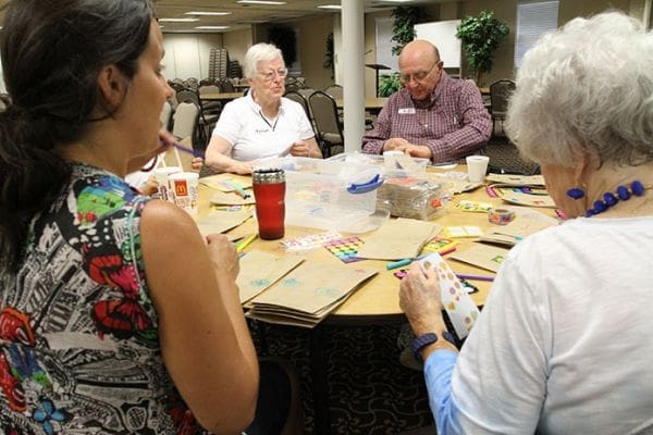 Elli Heaton, left, and Phyllis Moore, foreground, of Johnson Ferry Baptist Church, Marietta, and Joan and Ed Lucas, background, of Holy Family Church, Marietta, decorate the lunch bags with colorful art and words of encouragement. Photo By Michael Alexander
