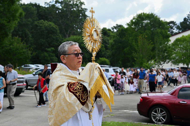 The congregation follows behind as Bishop Emeritus John Lee Juo-wang,  of the Diocese of Tainan, Taiwan, holds the monstrance high during the eucharistic procession  at Holy Name of Jesus Mission on the Solemnity of Corpus Christi on June 22.  Photo by Julianna Leopold