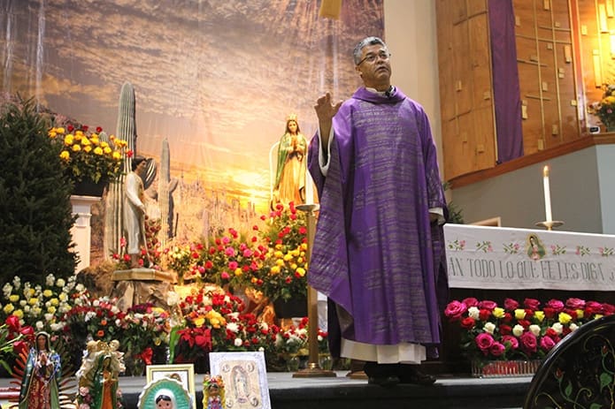 Father Luis Córdoba, administrator for Our Lady of the Americas Mission, Lilburn, stands at the altar as he gives his homily during the 5 p.m. Mass, one of seven Masses held throughout the feast day. In recognition of Our Lady of Guadalupe, the altar was filled with a massive number of flowers and a variety of items depicting the 