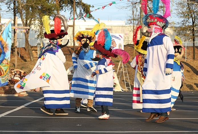 Performing in the rear parking lot at Our Lady of the Americas Mission, Lilburn, dancers with Chinelos San Marcos demonstrate a traditional dance from Morelos in south-central Mexico. Photo By Michael Alexander