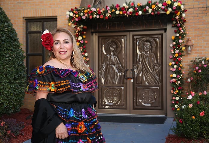 Guadalupe Torres, a catechist at Our Lady of the Americas Mission, Lilburn, stands by the Holy Door made by her son Jose Morales. Photo By Michael Alexander