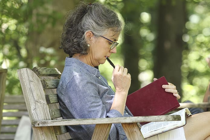 Kathleen Swann, a member of the Cathedral of Christ the King, Atlanta, takes time to journalize and read Scripture outdoors on the grounds of Ignatius House Jesuit Retreat Center July 31, the feast day of St. Ignatius of Loyola. Photo By Michael Alexander