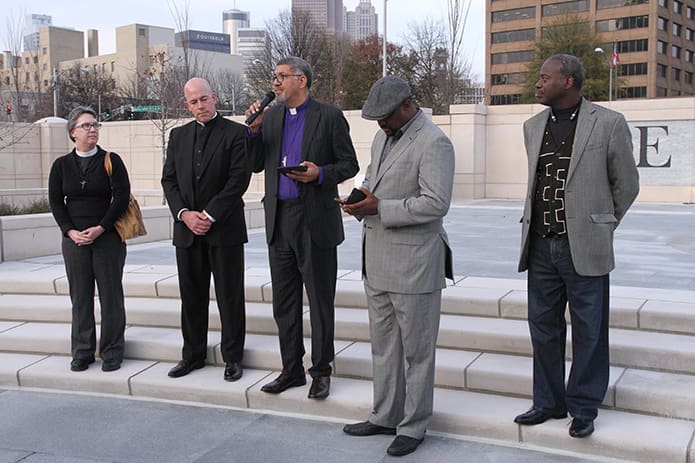 After a procession from the Shrine of the Immaculate Conception to Liberty Plaza, (l-r) Archdeacon Carole Maddux of the Episcopal Diocese of Atlanta, Father Kevin Peek, Archdiocese of Atlanta prison ministry chaplain, Bishop Robert C. Wright of the Episcopal Diocese of Atlanta, Rev. Derrick Rice, pastor of Sankofa United Church of Christ, Atlanta, and Mark Lomax of Atlantans Building Leadership for Empowerment (ABLE) stand before the congregation during the prayer vigil. Photo By Michael Alexander