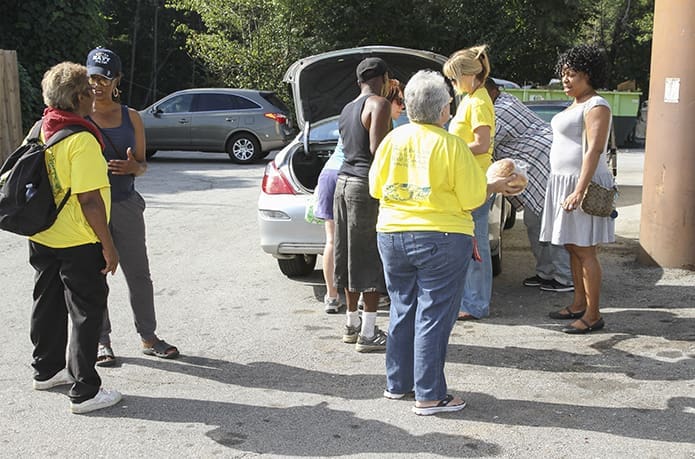 During the first of three stops, Sept. 24, going inside the perimeter along Donald Lee Hollowell Parkway, Just Faith Feed the Hungry volunteer Janice Smalley of World Changes Church, Marietta, second from the left, talks to a woman seeking food, Lauren Russell of St. Thomas the Apostle Church, Smyrna, center, passes out bread, and Hope Douglass of Buckhead Church, Atlanta, and Johanna Baldwin of St. Thomas the Apostle Church pass out soup from the trunk of a car. Photo By Michael Alexander
