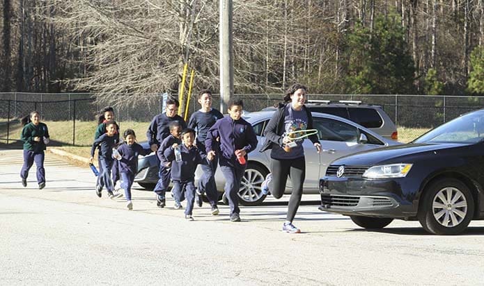 Christina Mirarchi, front, a seventh- and eighth-grade teacher at St. Peter Claver Regional School, Decatur, leads some student members of the Kilometer Kids on a run from the school to the upper parking lot as they prepare to begin a December 2017 practice. Photo By Michael Alexander