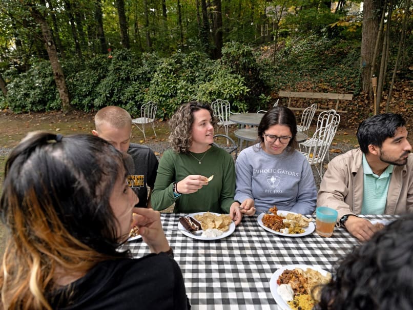 KSU Students gather at an outside table during free lunch at the Catholic Center. Photo by Johnathon Kelso