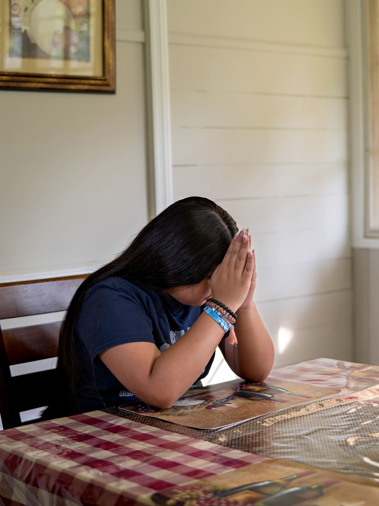 One of Brenda's daughters prays at the kitchen table before the Pilgrim Virgin Statue. Photo by Johnathon Kelso