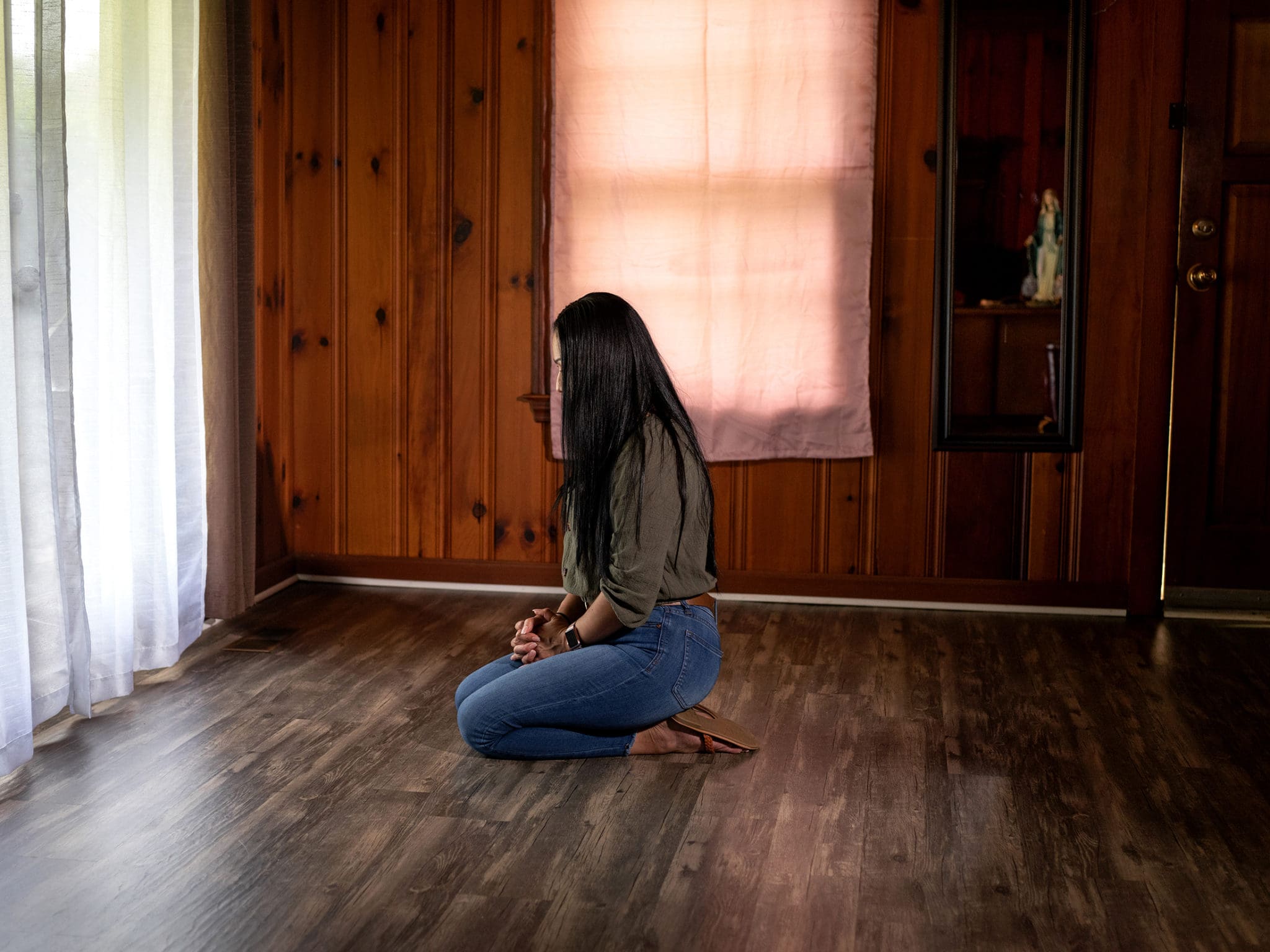 Brenda prays in a room at her home near the statue of Our Lady of Grace. The statue was brought by the Legion of Mary as part of their Pilgrim Virgin Statue Home Visitation Program. Legion members helped her family during a time of need. Photo by Johnathon Kelso