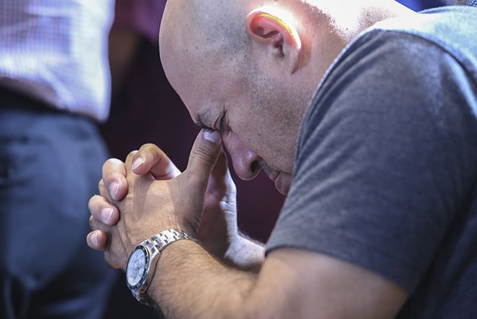 German Garzon prays at his chair after holy Communion during the 25th anniversary Mass at Lyke House. His daughter is a sophomore biology/pre-medicine major at Georgia State University, Atlanta, where Father Urey Mark also serves as chaplain. Photo By Michael Alexander