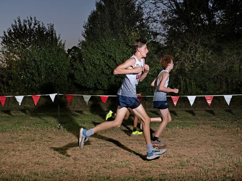 Marist runners Maddox Thomas, left, and Liam Wolfe, right,  compete during the Wingfoot XC Classic as the sun sets. Photo by Johnathon Kelso