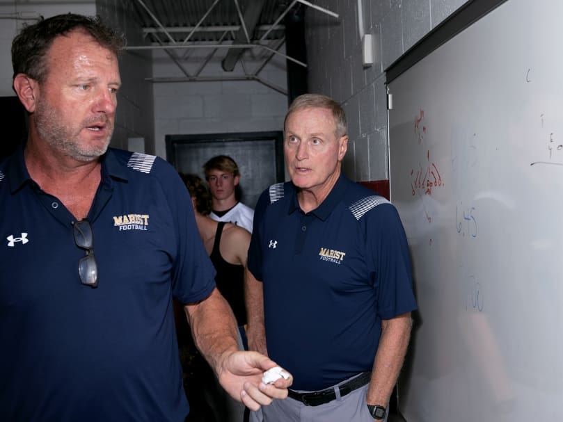 Marist Assistant Coach Paul Etheridge, left, goes over plays with Marist Head Coach Alan Chadwick, right, in the locker room before the game against Woodward Academy, traditionally known as the battle of the War Eagles. Photo by Johnathon Kelso
