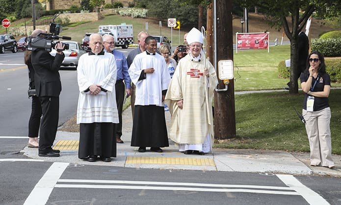 Bishop Joel M. Konzen, SM, right center, prepares to cross West Wesley Road on his way back to the Cathedral of Christ the King after visiting the overflow crowd at Second-Ponce de Leon Baptist Church. He was escorted by seminarian Avery Daniel, left center, and the cathedral’s Deacon Whitney Robichaux, third from left. Photo By Michael Alexander