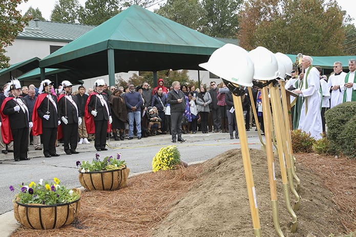 Twelve shovels are displayed in the foreground and in the background the congregation and Knights of Columbus honor guard listen as Father Darragh Griffith, pastor of Mary Our Queen Church, shares some words during the groundbreaking ceremony at the Norcross parish. Photo By Michael Alexander