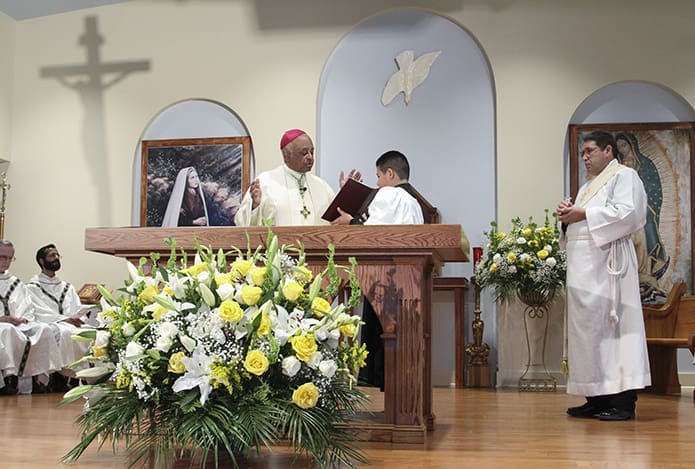 Archbishop Wilton D. Gregory, left center, conducts the prayer of dedication as Deacon José Orellana, right, holds the holy oil for the anointing of the altar and walls that followed the prayer. Photo By Michael Alexander