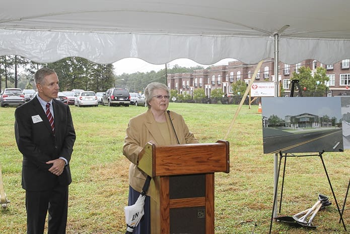 Standing under a tent on a rainy fall morning, Sister of Mercy Angela Ebberwein, vice president, mission, Mercy Care, opens the groundbreaking ceremony program with some words of reflection. Standing to the side is Mercy Care president Tom Andrews. Photo By Michael Alexander
