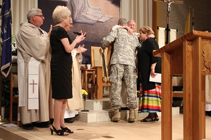 Msgr. Patrick Bishop embraces William F. Duffy, Major General, U.S. Army, and his wife Joy after they presented a framed American flag to the monsignor for his time-honored support of those serving in the military. Photo By Michael Alexander