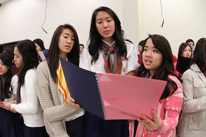 (L-r) Teenagers Brittany and Giang Ha and Mariana Do sing with the Our Lady of Vietnam Church choir during the celebratory Mass of dedication. Photo By Michael Alexander
