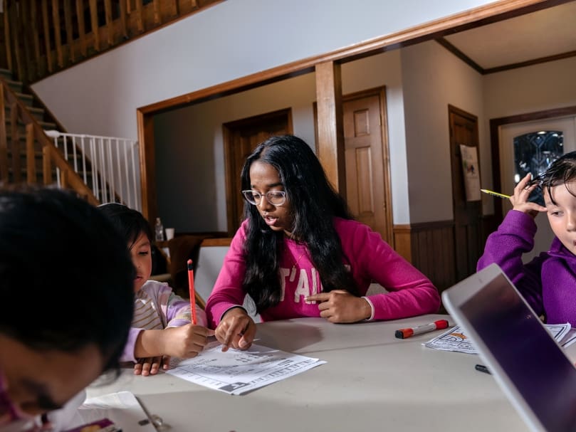 Tutor Geethika Janaki assists students with their homework  during an after-school program held at St. Brendan the Navigator Church. Students are also able to eat a meal there. Photo by Johnathon Kelso
