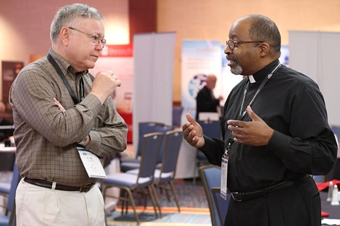 Father Bill Pruett of the Archdiocese of Oklahoma City, left, and Msgr. Edward Branch, chaplain of Lyke House, the Catholic Center at the Atlanta University Center, converse over a break at the annual convocation of the National Federation of Priestsâ Councils. Father Pruett and Msgr. Branchâs older brother served together in the U.S. Army during the Vietnam War. Photo By Michael Alexander