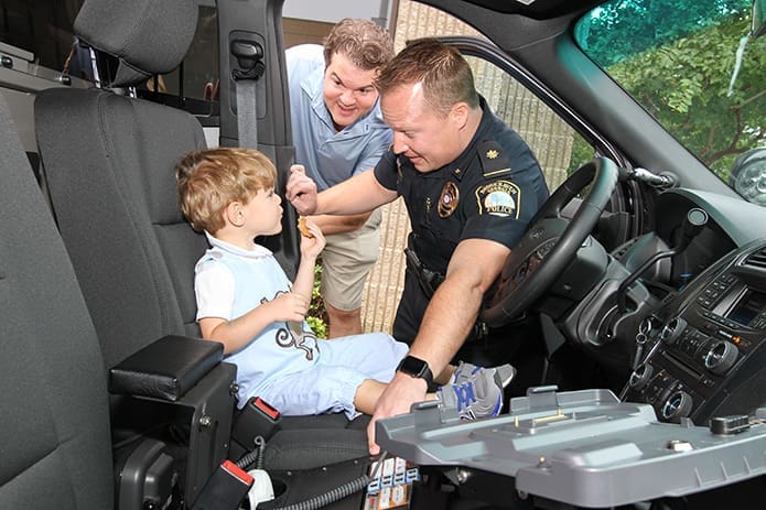 (Clockwise, from right) Brookhaven Police Department’s Major Brandon Gurley allows 2-year-old Thomas Gioia to sit behind the steering wheel of the Police Interceptor SUV, as his father Tom looks inside. Tom’s wife Ashlyn and his 4-year-old daughter, Eleanor, also came to the police station to visit Major Gurley. Photo By Michael Alexander