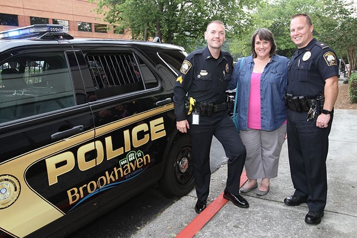 Anne Stephens, director of communications at Our Lady of the Assumption Church, Atlanta, stands between Sgt. Jake Kissel and Maj. Brandon Gurley of the Brookhaven Police Department. Stephens works closely with the two officers in coordinating the Adopt-A-Cop Program. Photo By Michael Alexander