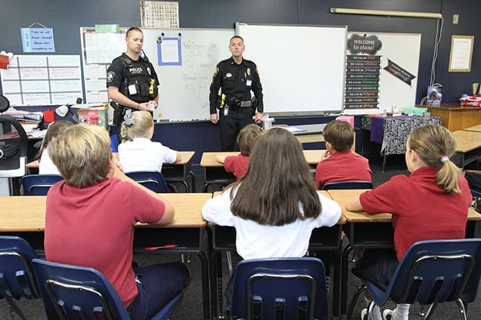 Sgt. Jake Kissel, right, of the Brookhaven Police Department makes his first visit of the school year, Sept. 14, to Kathryn Berg’s fifth grade class at Our Lady of the Assumption School. Sgt. Kissel, who was adopted by the entire fifth grade, which includes two other classrooms, brought police K9 handler Officer David Fikes, left, as a special guest. Photo By Michael Alexander