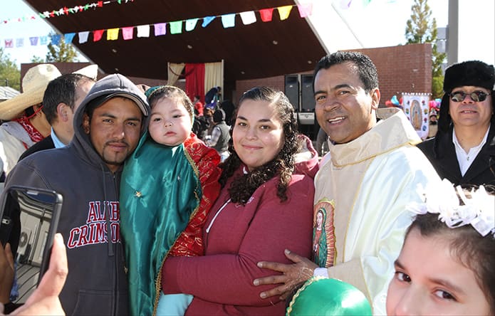 (L-r) Juan Landeros, his one-year-old daughter Anayeli dressed up in an Our Lady of Guadalupe costume, and his wife Maribel pose for a photo with Father Jose Duvan Gonzalez, parochial vicar at St. Joseph Church, Dalton. Photo By Michael Alexander