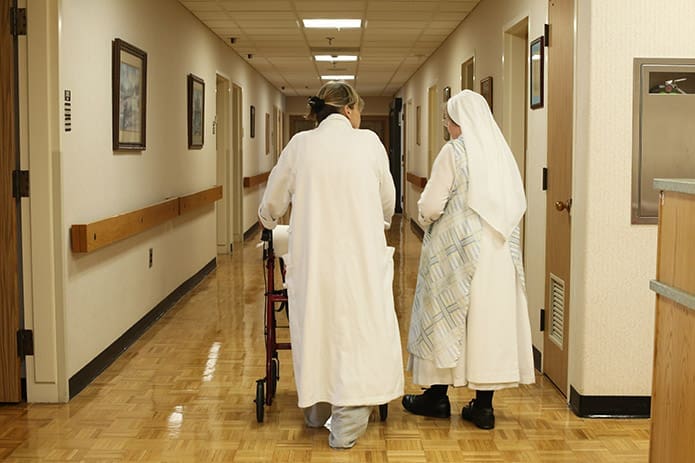 Patient Pamela Hughes, left, returns to her second floor room, accompanied by Hawthorne Dominican Sister Mary Kateri. Photo By Michael Alexander