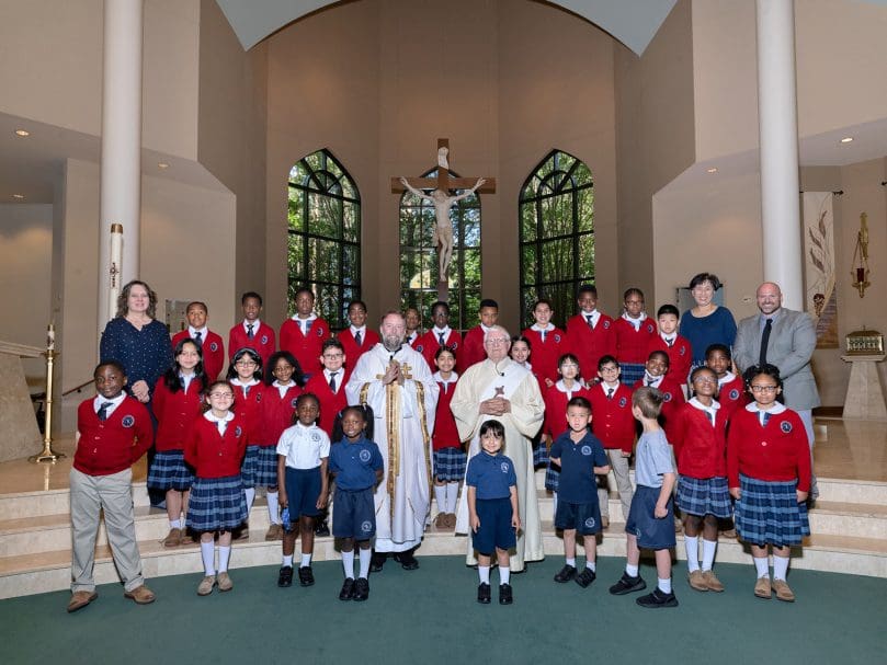 Father Kevin Hargaden, left center, and Deacon Gayle Peters, right center, are seen with students and faculty following the last school Mass for Our Lady of Victory School at St. Matthew Church in Tyrone.  Pictured far left, instructor Lisa Shupenus, and far right, music teacher Seong Cho and Principal George Wilkerson. Photo by Johnathon Kelso