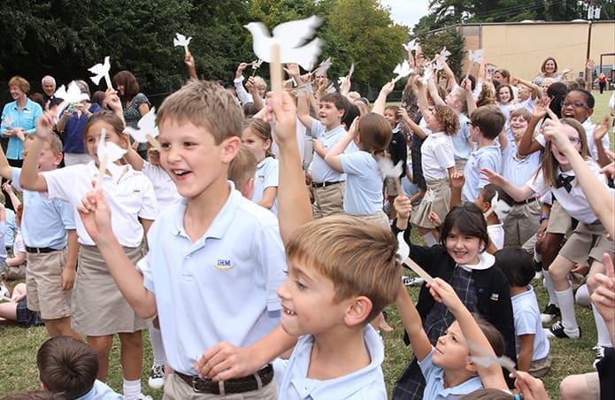 With raised doves on a stick made by art teacher Susan Cartwright, some of the Immaculate Heart of Mary School second graders react enthusiastically as a jet flies over the back field, where they gathered for a symbolic welcome of Pope Francis to the United States. Photo By Michael Alexander