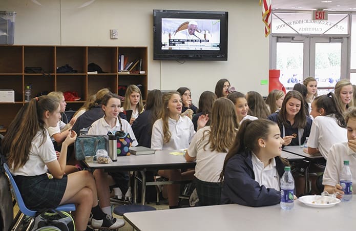 St. Pius X High School students in Atlanta gather in the cafeteria during lunch as Pope Francisâ talk to the Archdiocese of Washingtonâs Catholic Charities office is carried over live news on an overhead monitor. Photo By Michael Alexander