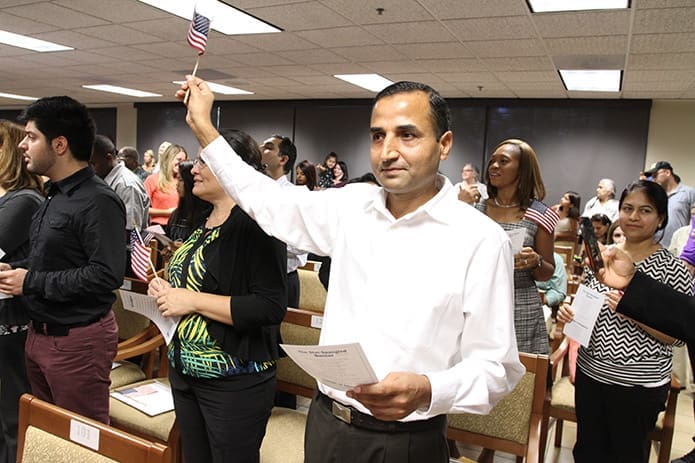 In a moment of happiness and pride, Pasupati Regmi raises his flag after completing his oath of allegiance, officially making him an American citizen. Regmi participated in the Aug. 29 ceremony with 163 people from 63 different countries at the U.S. Citizenship and Immigration Services office in Atlanta. Photo By Michael Alexander