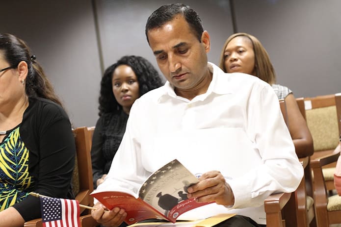 Regmi reads through some citizenship documentation as he waits for the ceremony to begin. Photo By Michael Alexander