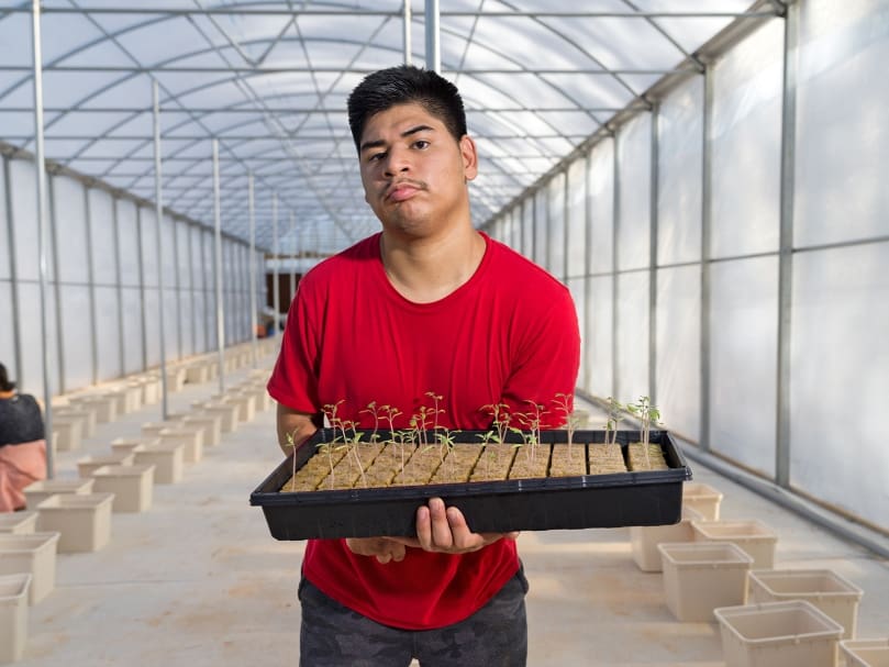 Joseph Newton holds a tray of tomato seedlings inside the greenhouse at Peachtree Farm, which provides employment opportunities for men and women with disabilities. Photo by Johnathon Kelso