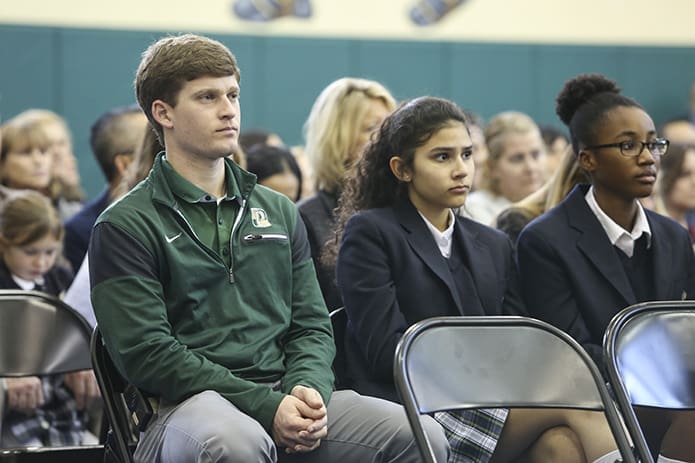 (L-r) Jonathon Oshinski, Pinecrest Academy middle school P.E. teacher and middle school boys basketball coach, sits with eighth-graders, Gabi Rodriguez and Jada Green, during the Feb. 2 Founder’s Day Mass. Oshinski is 2010 graduate of Pinecrest Academy. Photo By Michael Alexander