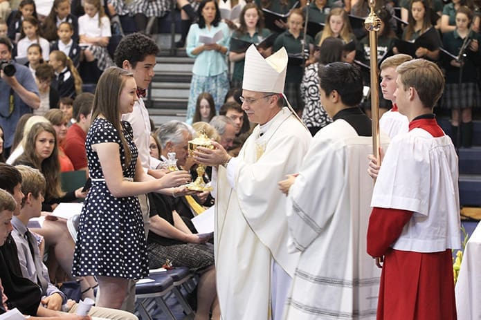 Bishop Luis Zarama was the main celebrant for Pinecrest Academy’s 20th anniversary Mass. Seniors Heather Bailer and Jose Medina bring up the gifts during the offertory procession. Photo By Michael Alexander