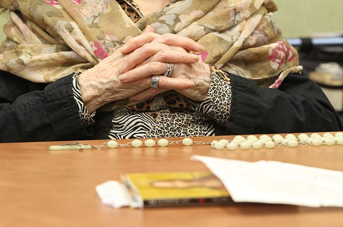 Some of the residents like 90-year-old Pat Swenson, may not be able to hold the rosaries, so they spread them out over the table, occasionally touching the beads. David Waters brings this rosary, which belonged to his late grandmother, from home each week so Swenson can use it. Photo By Michael Alexander