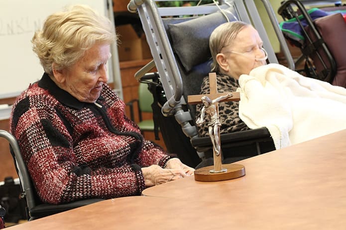 Pennsylvania native Mary Warren, left, and Nebraska native Irene Crow join eight other fellow residents in praying the Luminous Mysteries of the rosary Nov. 29. On the table resting between them is a âgift of the Holy Spirit crucifix.â Photo By Michael Alexander