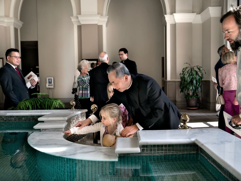 Father Francis Tran Quoc Tuan helps a young parishioner at the holy water font at Holy Vietnamese Martyrs Church the morning of the ordination to the priesthood. Photo by Johnathon Kelso