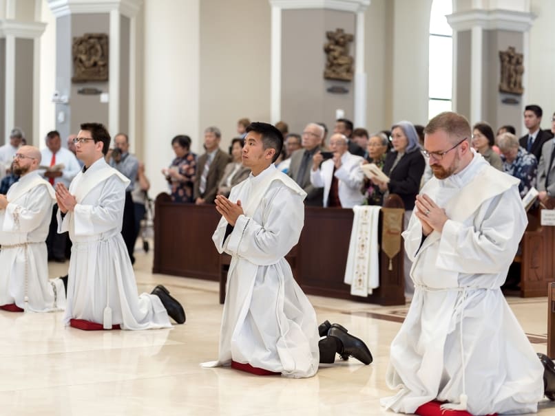 Deacon Nicholas Le, center, kneels before the altar with the other deacons during the ordination to the priesthood. Photographed, from left to right, are Deacon Matthew Howard, Deacon Pete Coppola, Deacon Le and Deacon Evan Glowzinski. The ordination was May 27 at Holy Vietnamese Martyrs Church, Norcross.  Photo by Johnathon Kelso