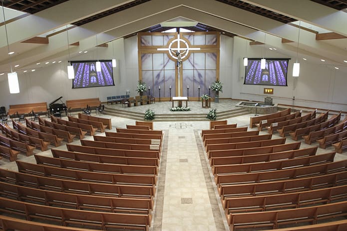 An overhead view of the refurbished sanctuary at Prince of Peace Church, Flowery Branch, reveals that wooden pews have replaced chairs, a new reredos towers behind the altar and a new baptismal pool appears to the right of the altar. Photo By Michael Alexander