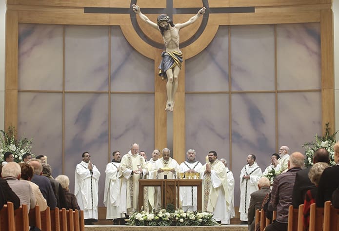 Archbishop Wilton D. Gregory, center, stands before the altar among his fellow clergy during the Liturgy of the Eucharist. The corpus of Jesus, which is part of the new reredos, is approximately 8 feet tall and weighs approximately 350 pounds. Photo By Michael Alexander
